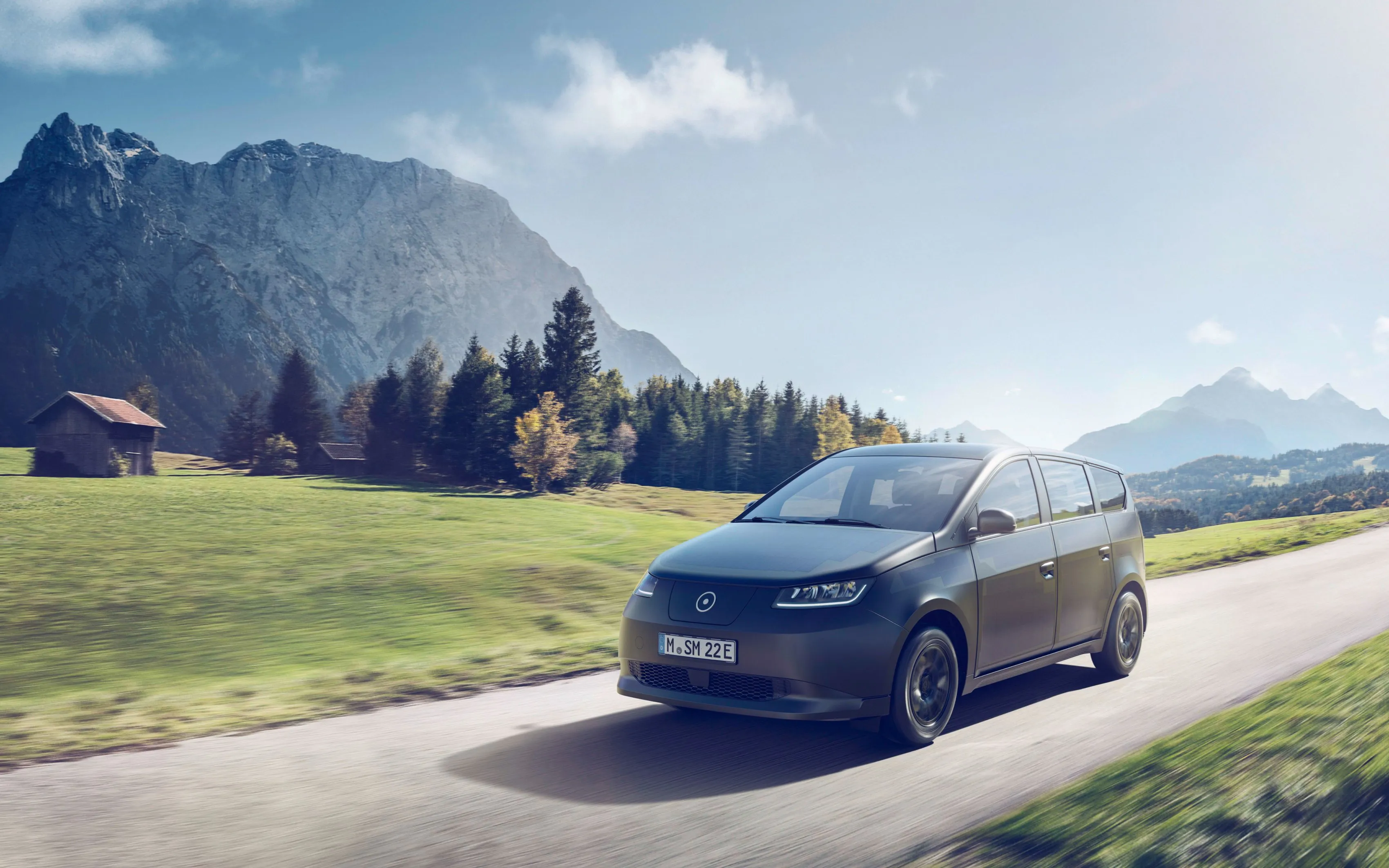 a car on a road with grass and mountains in the background